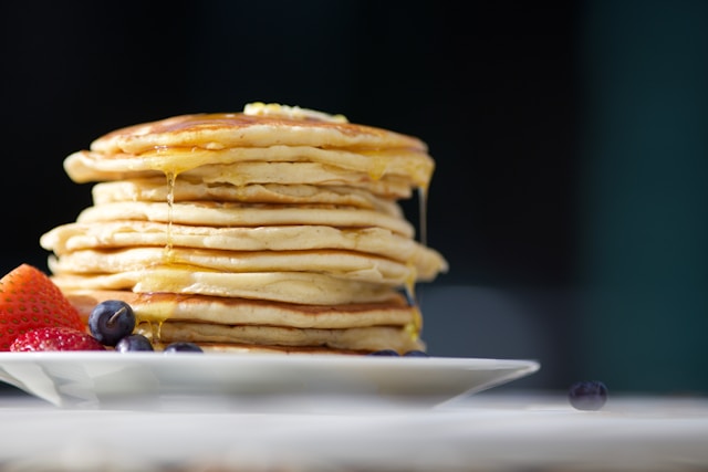 Stack of fluffy Japanese pancakes topped with whipped cream and fresh fruit in Tokyo café